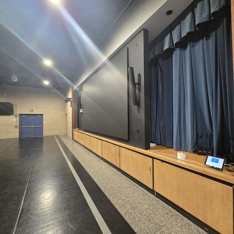 Auditorium large-format — Large-format display flown beside the stage, with control at the cabinet run below.
