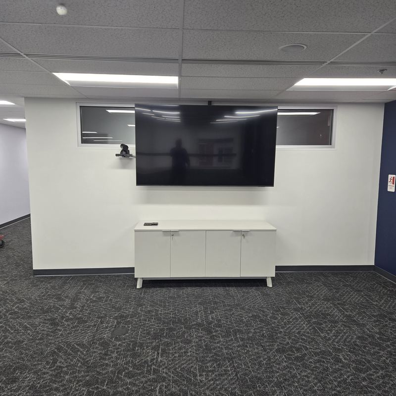 Conference room — Display and camera above a credenza, flanked by interior glazing.