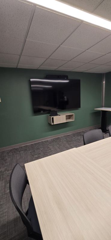Meeting room — Display and soundbar on a colour-blocked wall, mounted to clear the table edge.