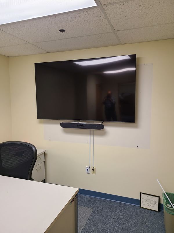 Huddle space — Display with soundbar and camera, set into a partitioned office floor.