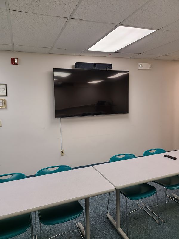 Training room — Wall-mounted display with an integrated video bar above, serving a full classroom layout.